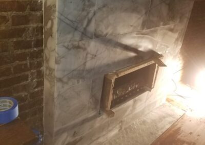 A white marble fireplace with a wooden mantle