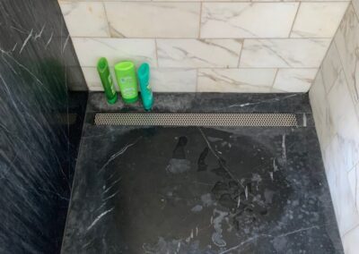 A shower with a black marble floor and walls