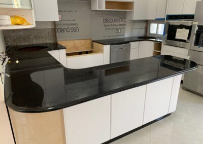 A kitchen with white cabinets and black counter tops
