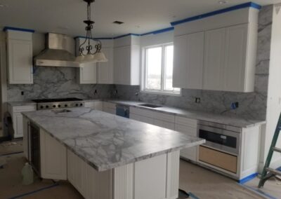 A kitchen with a marble counter top and white cabinets