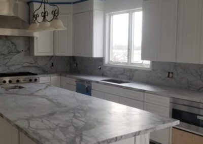 A kitchen with marble counter tops and white cabinets