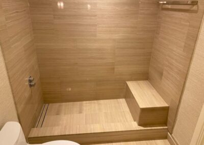 A bathroom with a toilet and a wooden bench