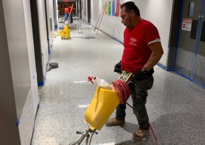A man using a floor scrubber in a hallway