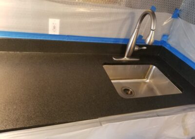 A stainless steel sink with a black counter top